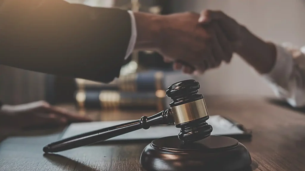 Gavel in focus, handshake in background—legal agreement.